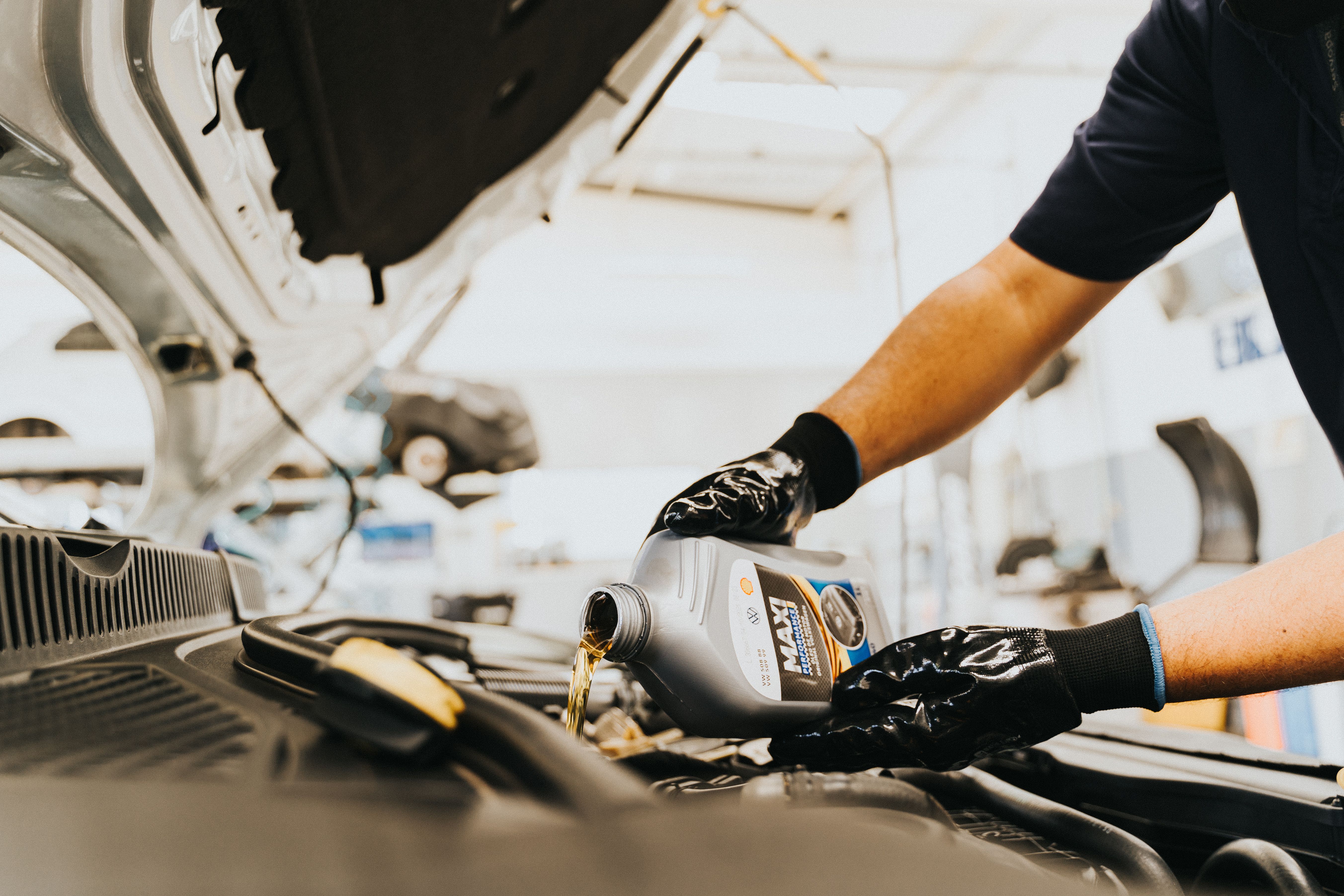 Motor oil bottles and engine oil being poured during vehicle maintenance